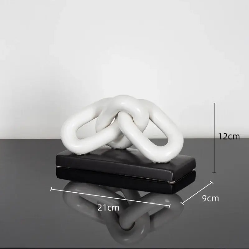 White ceramic chain sculpture on black base as modern home decoration figurine contrasting golden chain style