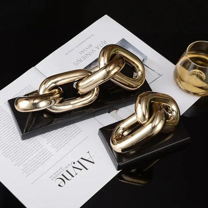 Gold-toned glossy metal chain link home decoration figurine displayed on black base for modern living room decor