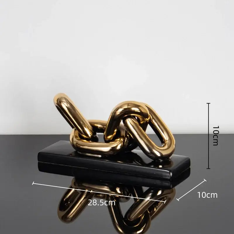 Modern golden chain home decoration figurine sculpture in shiny gold resting on a sleek black rectangular base