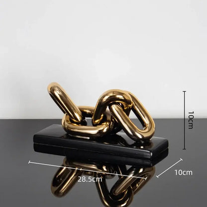 Modern golden chain home decoration figurine sculpture in shiny gold resting on a sleek black rectangular base