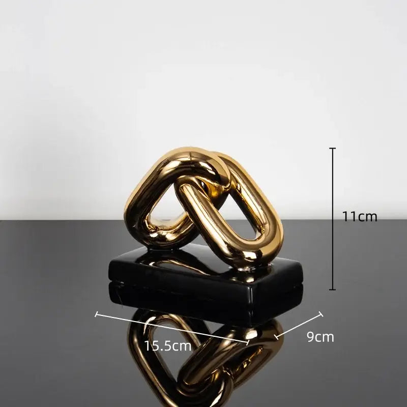 Modern golden chain home decoration figurine in glossy gold finish resting on sleek black base for living room decor