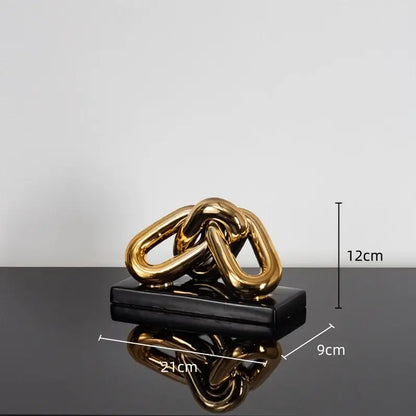 Modern golden chain home decoration figurine in metallic gold resting on black rectangular base for living room decor