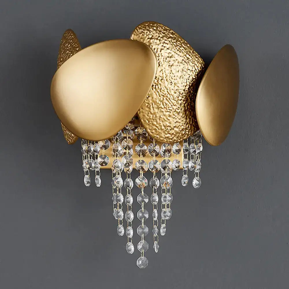 Modern golden egg wall mount light with gold-toned textured and smooth oval plates and dangling crystal beads