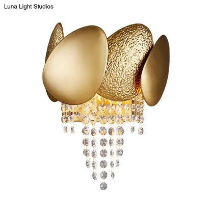 Modern golden egg wall mount light with textured and smooth oval panels and cascading crystal beads for bedroom