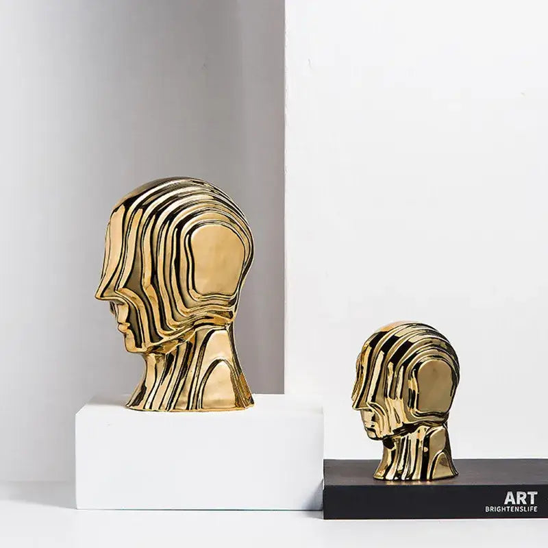 Two golden abstract geometric ceramic head sculptures with flowing contours for modern living room decorbites decor