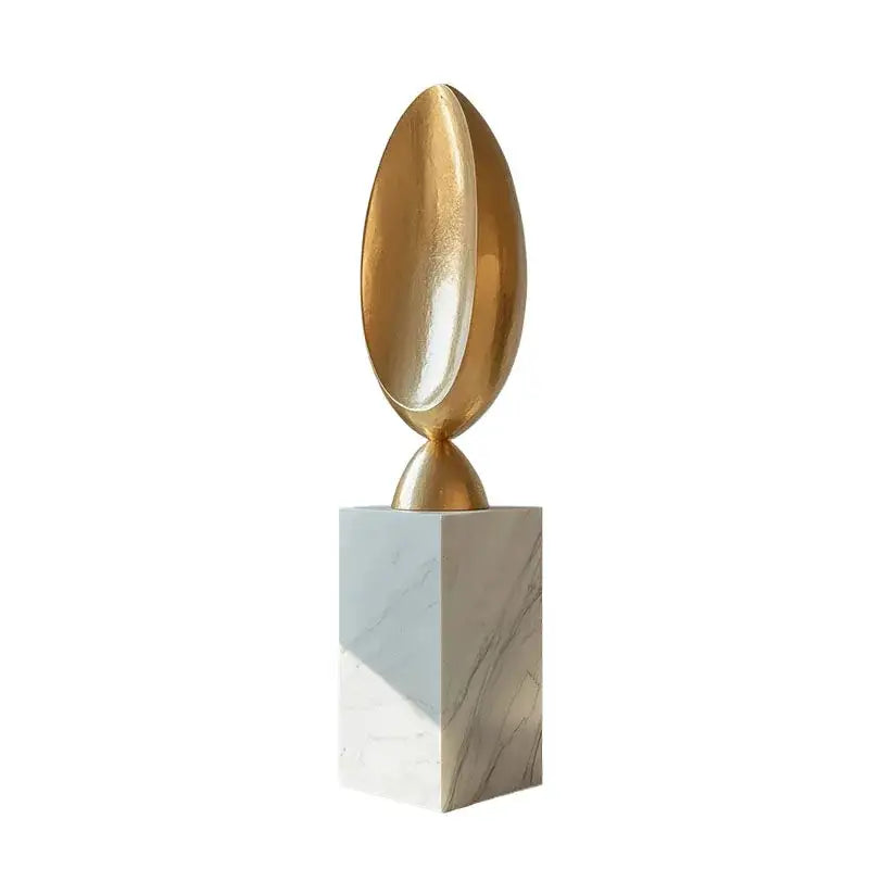 Modern golden geometric resin sculpture featuring a golden metallic egg shape on a white marble pedestal for home decor