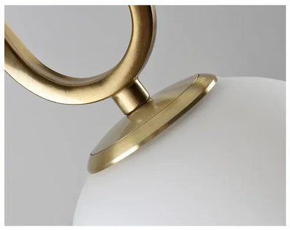 Modern golden glass ball pendant light with sleek brass finish and smooth white glass globe in an oval metal frame