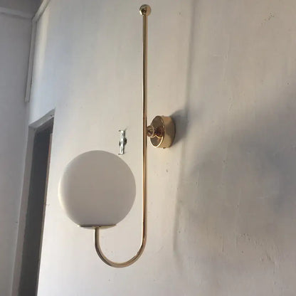Modern golden gooseneck wall sconce with frosted glass ball shade and sleek curved metal arm for bedroom lighting