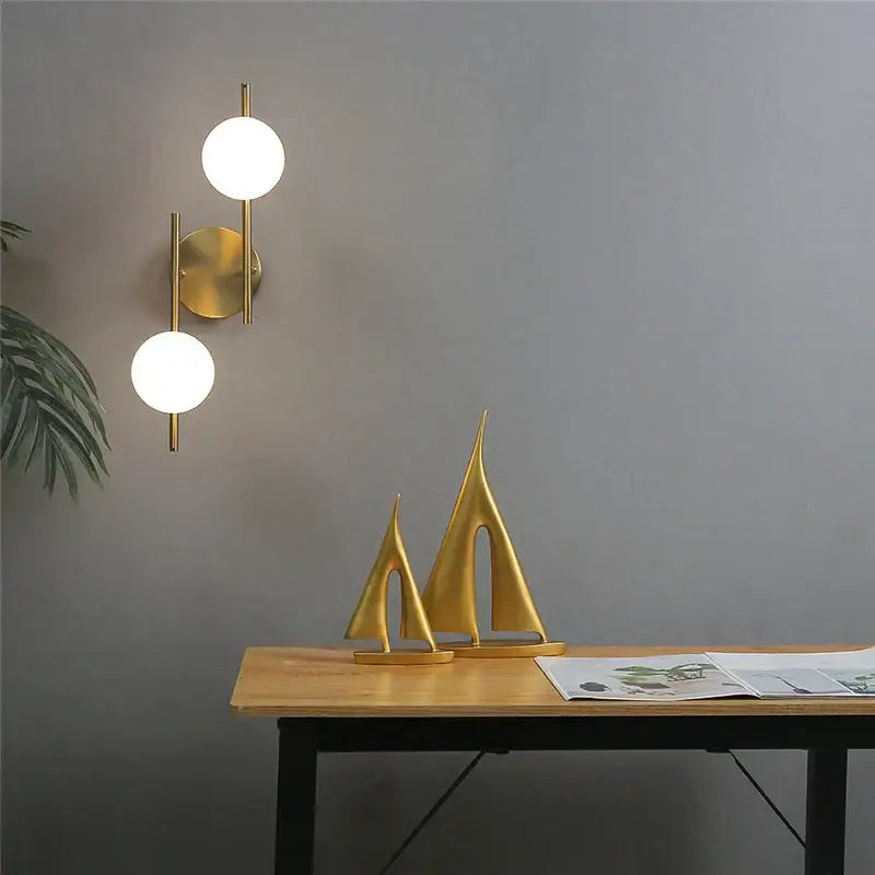 Modern golden led wall lights featuring a gold-colored minimalist sconce with two milky glass spheres from decorbites golden led