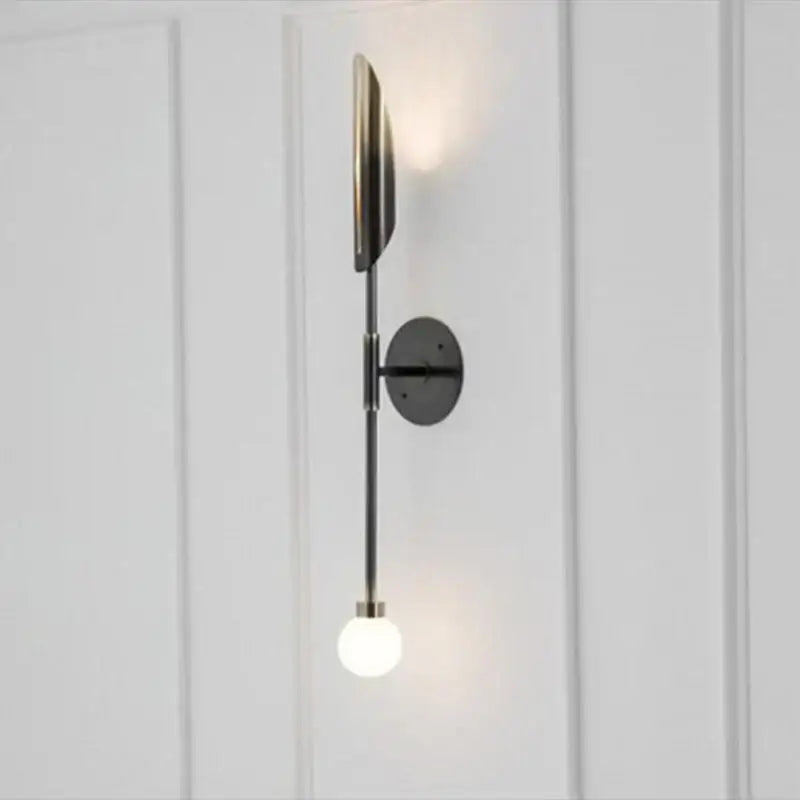 Modern golden metal glass wall lamp with sleek black metal sconce featuring an illuminated globe bulb decorbites golden metal wall lamp