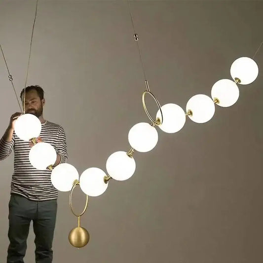 A modern golden necklace chandelier with frosted white glass globes and polished brass rings for dining room luxury lighting
