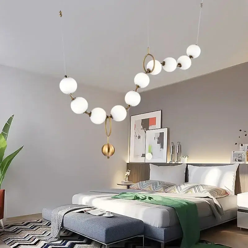 A modern golden necklace chandelier with white glass globes and gold-toned metal arms for dining room luxury lighting