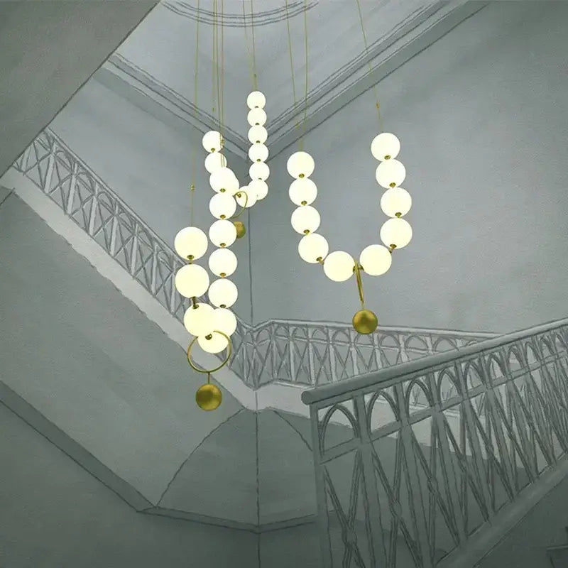 Modern golden necklace chandelier with glowing white spherical bulbs and gold-toned metallic accents for dining room luxury light
