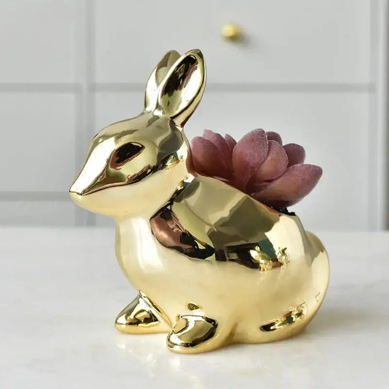 Modern golden ceramic flower pot shaped like a rabbit with a glossy finish holding a purple succulent for living room