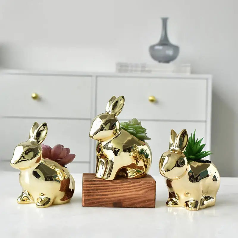Modern golden ceramic flower pots shaped as reflective rabbit planters with small succulents for living room decor