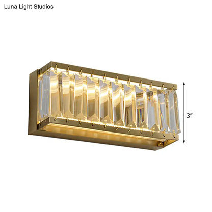 Modern golden rectangle led wall sconce with clear faceted crystal prisms refracting warm light and gold finish