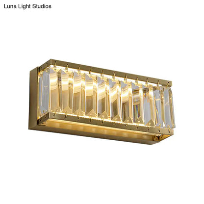 Modern golden rectangle led wall sconce with gold finish and clear faceted crystal prisms refracting warm light
