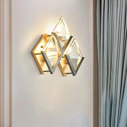 Modern style wall sconce light with clear crystal triangular facets and a dual-tone golden metallic frame for bedroom use