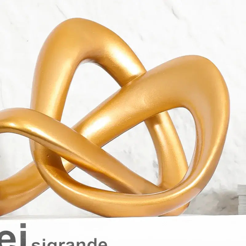 Modern golden twisted dough rope knot sculpture with glossy smooth intertwined loops for living room decor