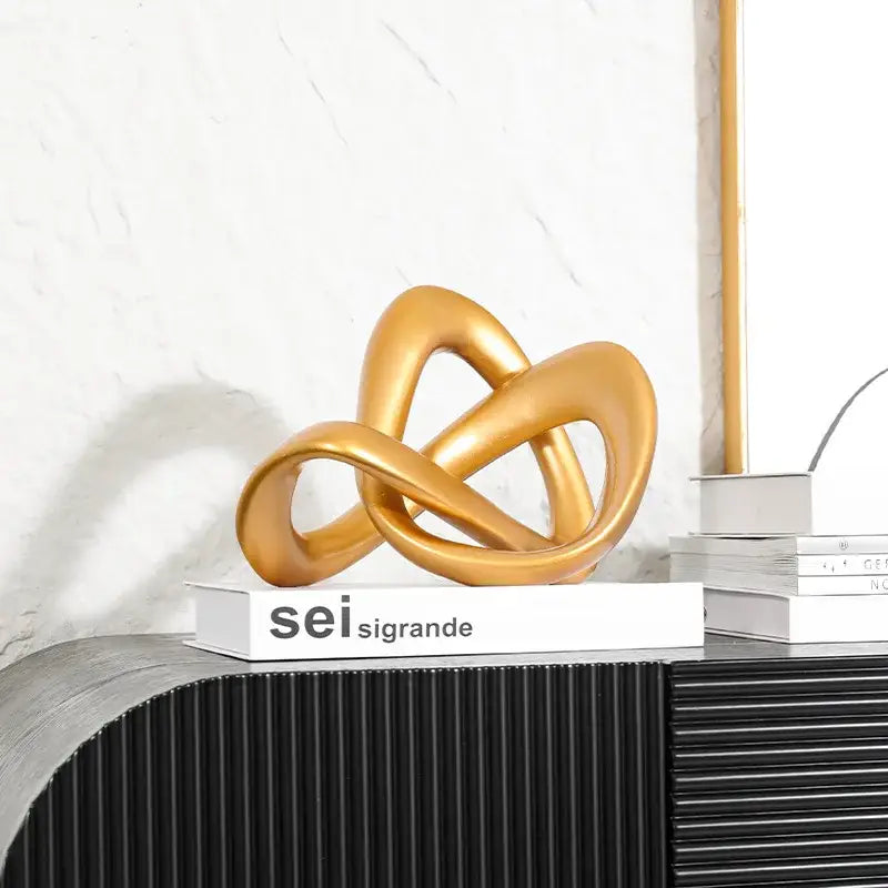 Modern golden twisted dough rope knot sculpture made of smooth polished material for living room decor
