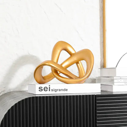 Modern golden twisted dough rope knot sculpture made of smooth polished material for living room decor