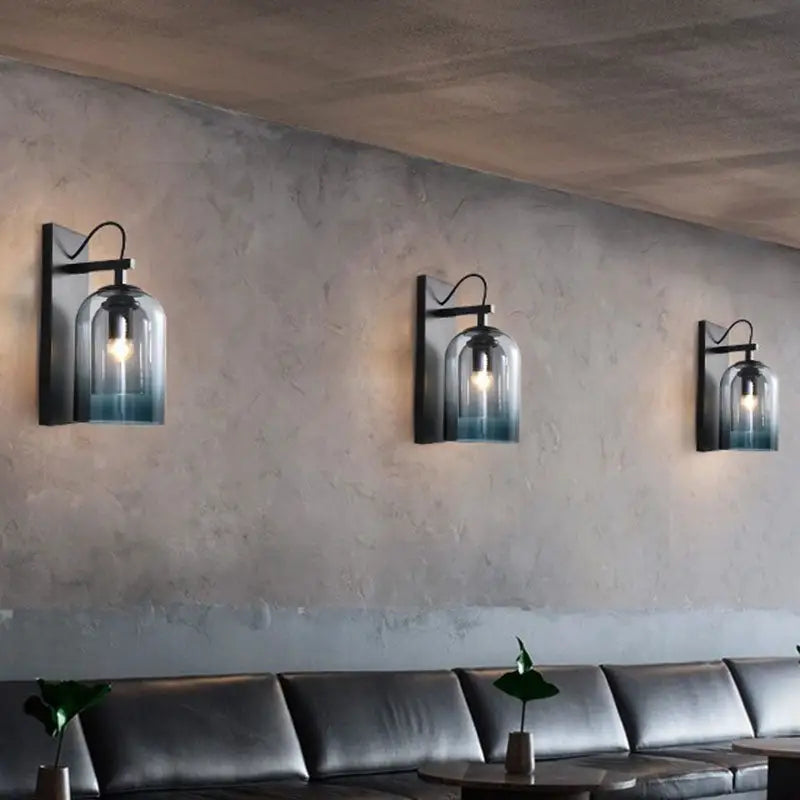 Three black metal wall-mounted lamps with clear modern gradient glass shades in blue for bedroom sconce lighting fixture