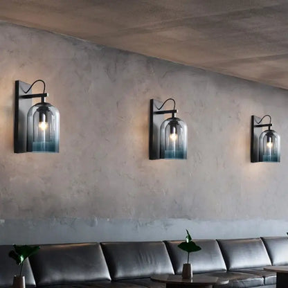 Three black metal wall-mounted lamps with clear modern gradient glass shades in blue for bedroom sconce lighting fixture