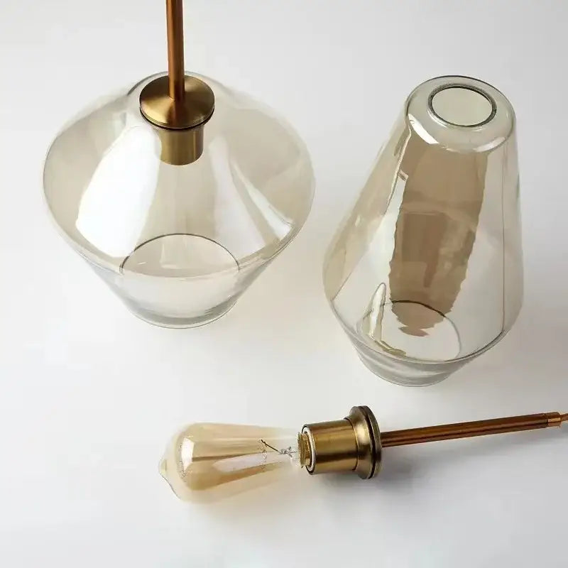 Two smoked gray amber glass pendant lamps with brass hardware and amber filament bulbs for dining room decorbites lighting