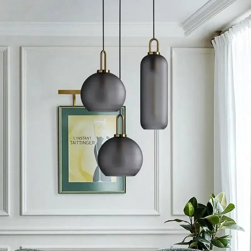 Modern gray and brass glass pendant light fixture with brass accents hanging for kitchen lighting use