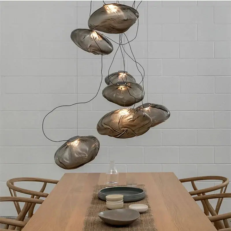 Modern gray cloud glass pendant lights featuring irregular translucent amber glass shades suspended by thin black wires