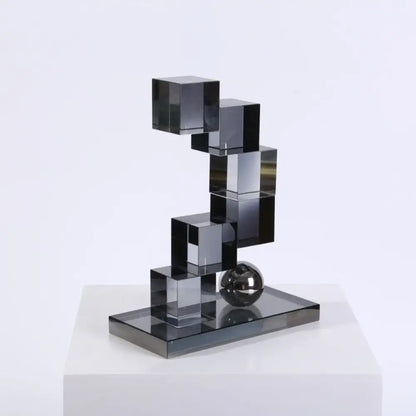 Modern gray geometric crystal glass decor featuring stacked black translucent cubes and a metallic sphere on a mirrored base