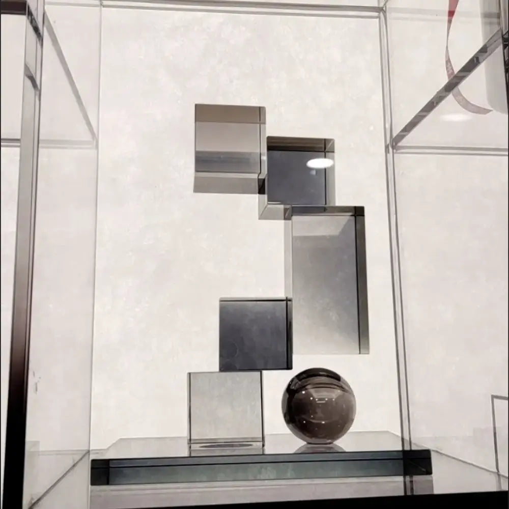 A sleek dark gray crystal glass sphere on a black base with tiered reflective metallic cubes decorbites geometric crystal glass ornament