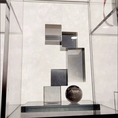 A sleek dark gray crystal glass sphere on a black base with tiered reflective metallic cubes decorbites geometric crystal glass ornament