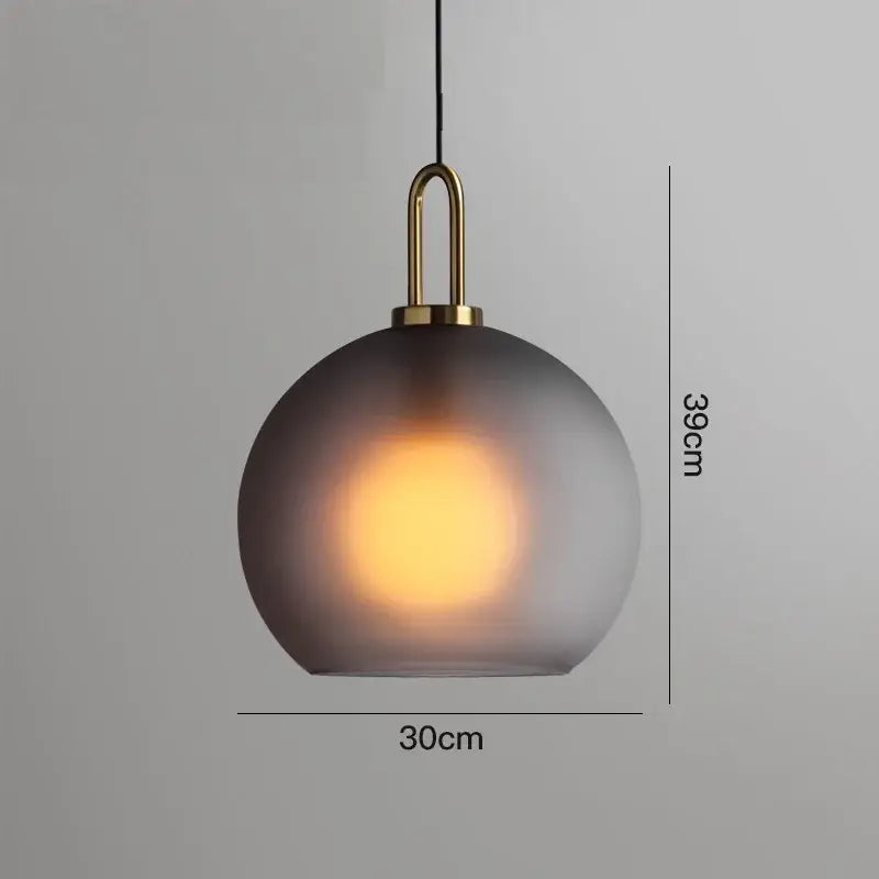 A sleek modern gray glass ball led pendant light with frosted shade and polished brass hardware for dining room decorbites