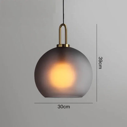 A sleek modern gray glass ball led pendant light with frosted shade and polished brass hardware for dining room decorbites