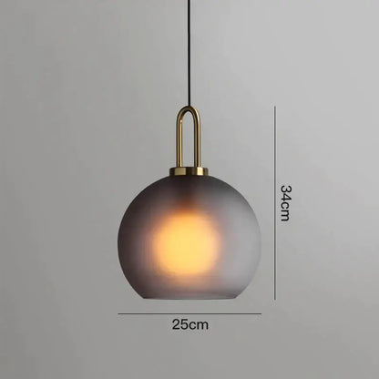 A sleek modern gray glass ball pendant light with frosted shade and brass accents ideal for dining room decorbites