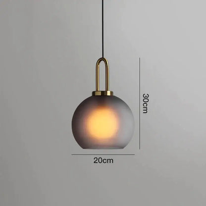 A sleek modern gray glass ball pendant light with frosted shade and brass accents ideal for dining room decorbites