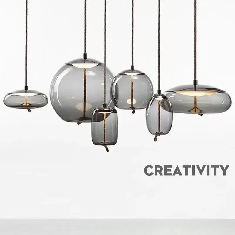 Set of modern gray glass knot pendant chandelier lights with translucent shades and black cords for dining room use