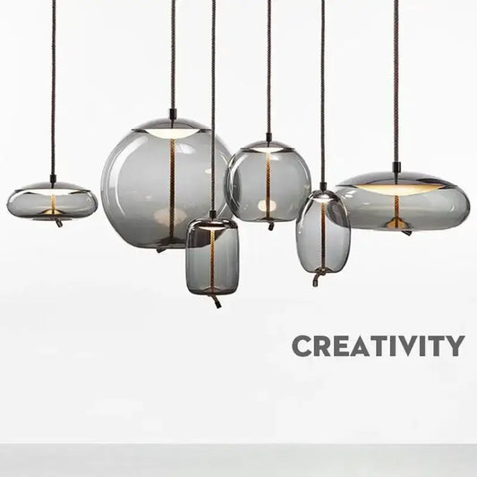Set of modern gray glass knot pendant chandelier lights with translucent shades and black cords for dining room use