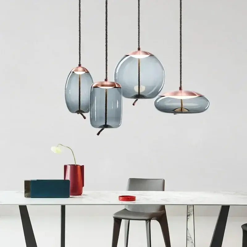Set of four modern gray glass knot pendant chandelier lights with frosted shades and copper accents for dining room