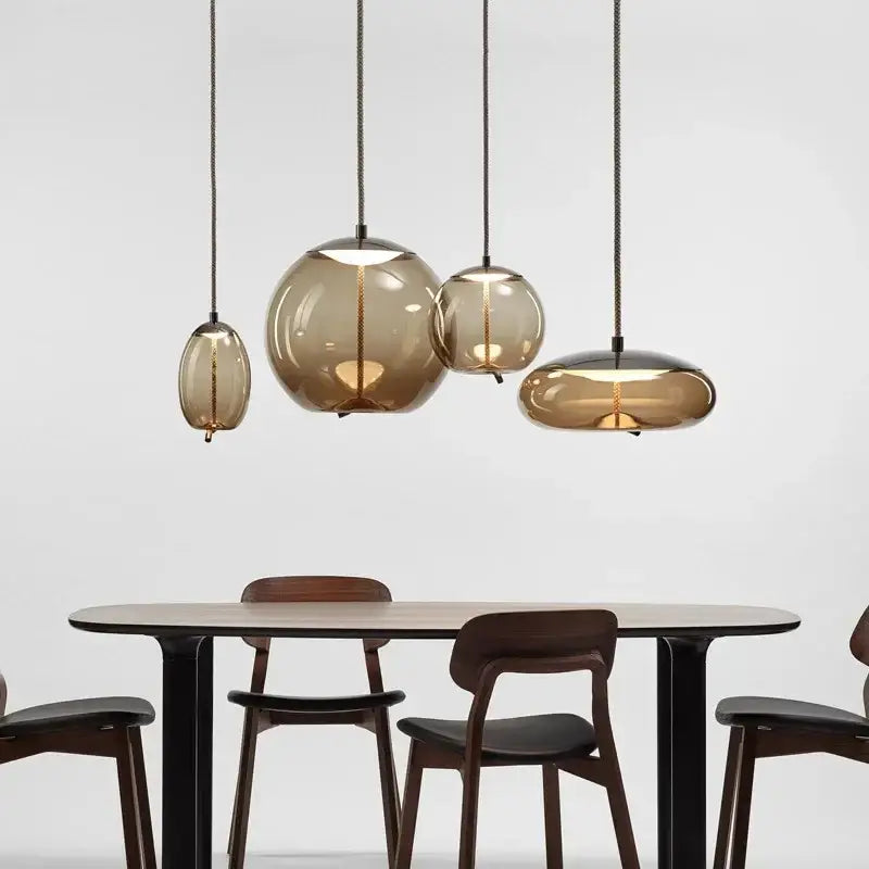 Set of four amber-tinted glass knot pendant chandelier lights with modern spherical shapes for dining room use