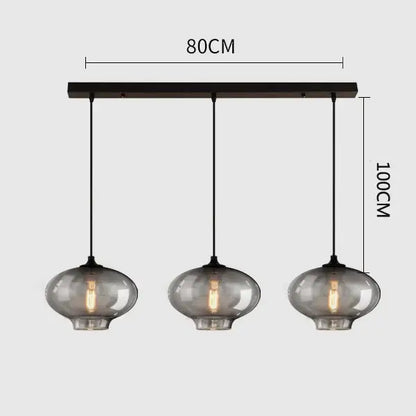 Modern black metal pendant light with three gray glass smoked globes featuring exposed filament bulbs for dining room