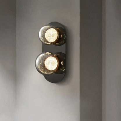 Modern gray glass wall lights with two crackled spherical bulbs in a matte black metal frame for living room use