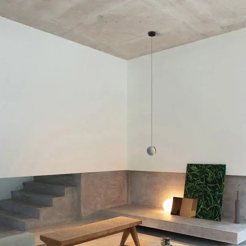Minimalist spherical pendant light with matte gray finish and black cord in modern gray and gold decorbites cement chandelier