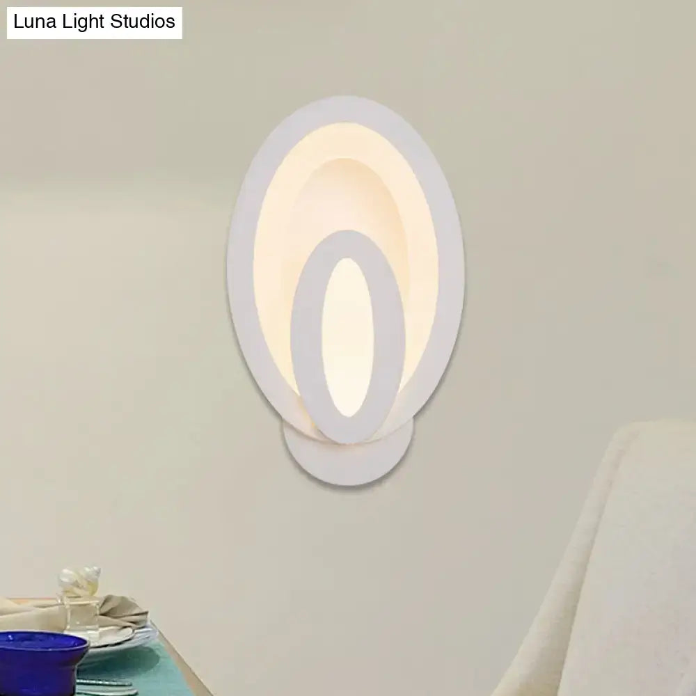 Modern white oval wall sconce with concentric circular design and warm white ambient lighting for direct wired electric use