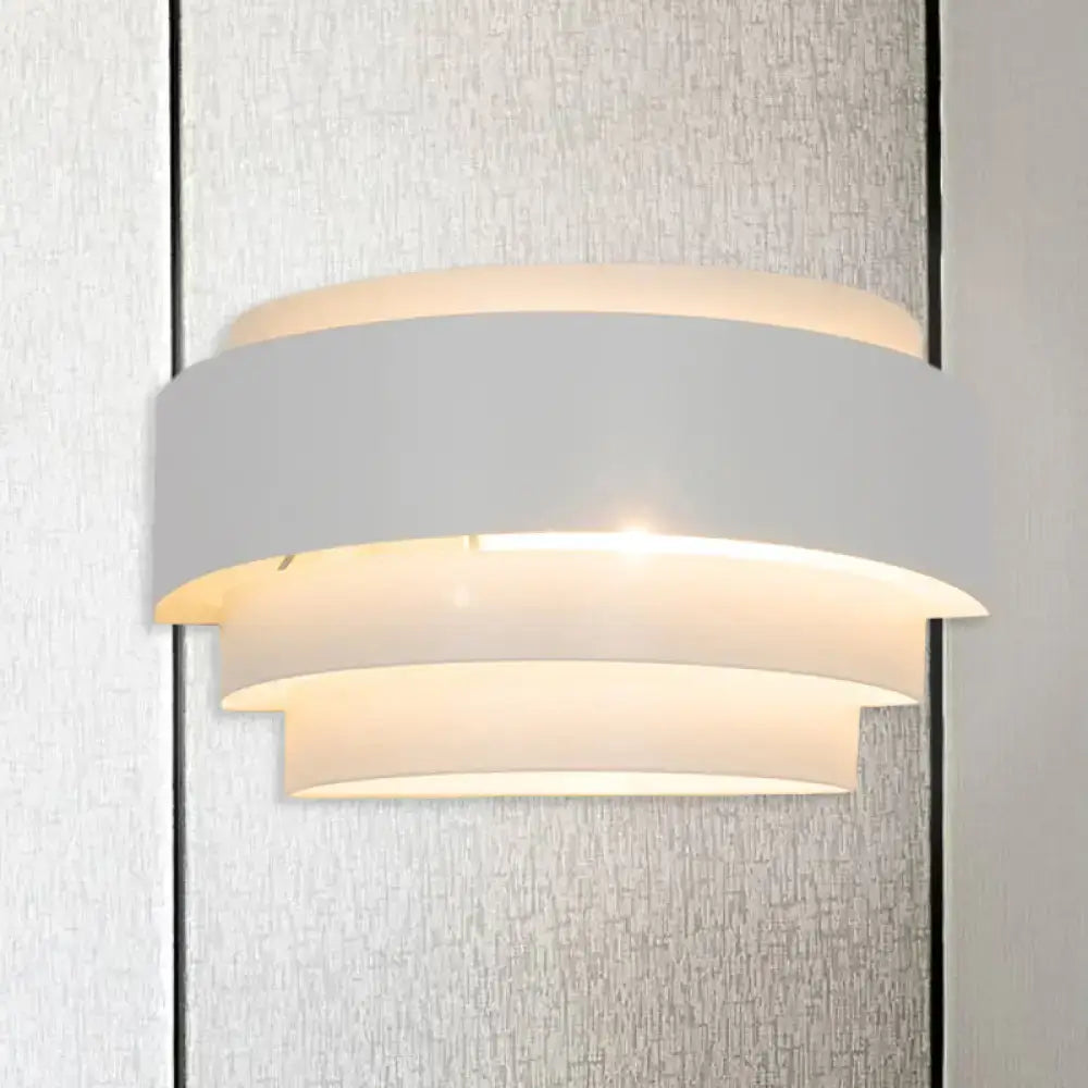 Modern gray metal wall sconce with layered curved shades emitting warm glow for living room lighting