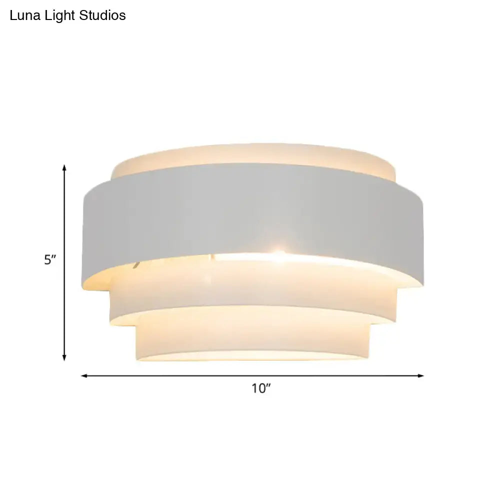 Modern gray metal wall sconce with tiered matte white fabric shades emitting warm glow for living room lighting