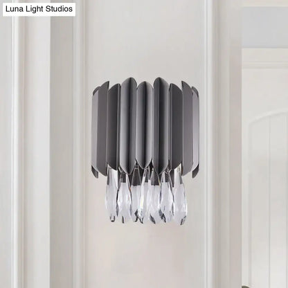 Modern gray metallic wall sconce with sleek blades and dangling clear crystal teardrop accents for bedroom lighting