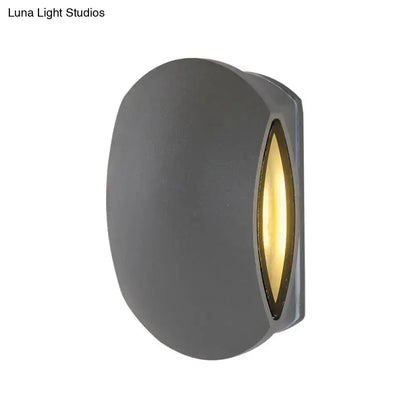 Modern gray oval outdoor wall light with warm white bulb included emitting golden light from elongated lens