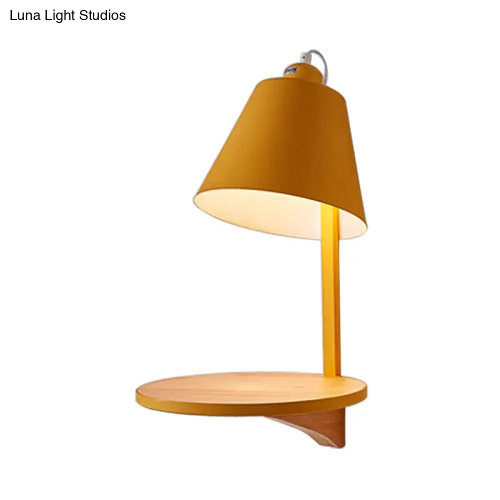 A warm amber modern gray tapered shade wall sconce with a wooden shelf and cylindrical metal stem for bedroom lighting